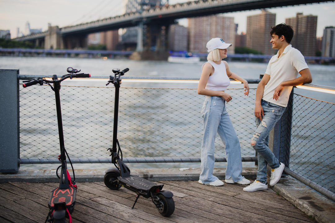 a man and a woman with kaabo mantis 8 scooter by the river 