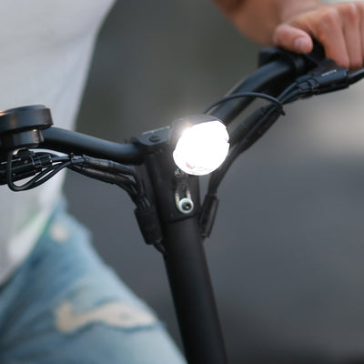 Illuminated LED headlight on a Kaabo electric scooter's handlebar, highlighting the scooter's lighting feature for safe night riding.