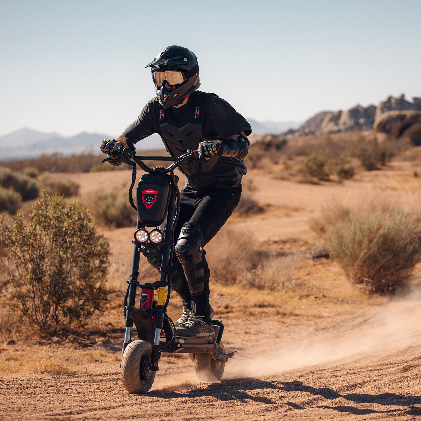 Adventurous rider tackling a dusty trail on the Kaabo Wolf Warrior 11 Pro+ electric scooter, showcasing its dust-kicking power and rugged outdoor performance.